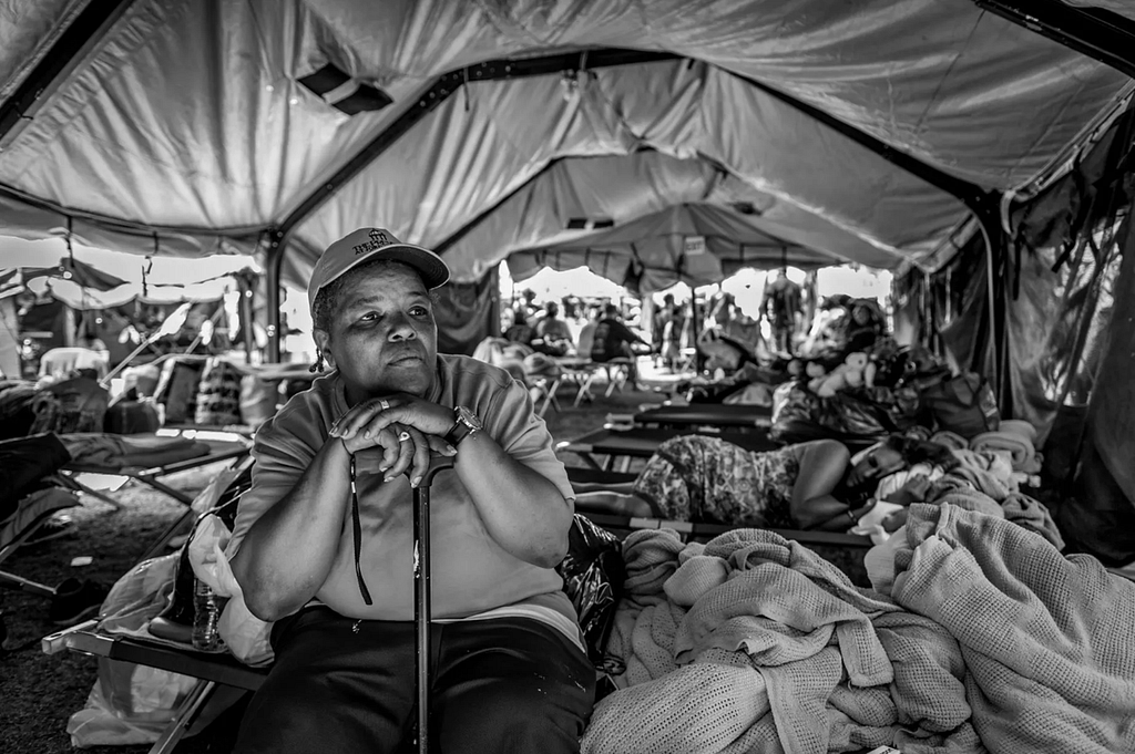 Black woman sitting at her spot in a tent encampment