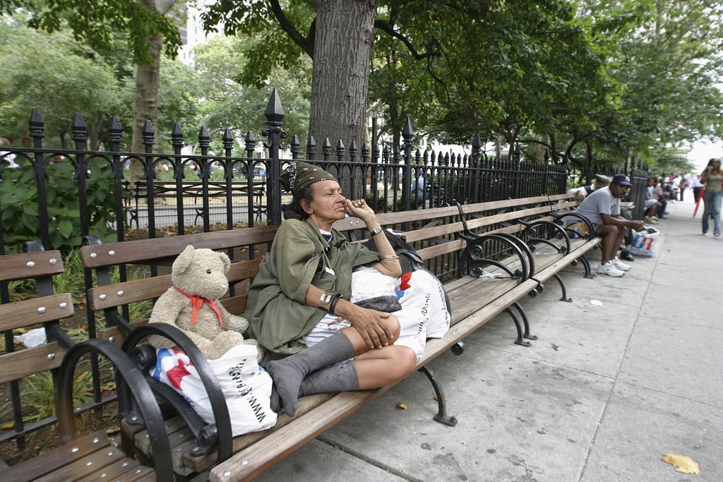 Homeless woman sitting on bench in park
